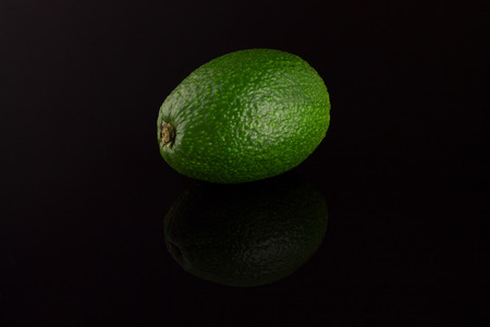Avocado green on a black background with reflectionの写真素材