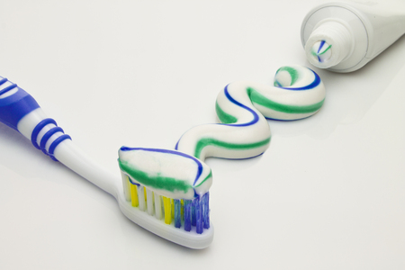 Toothbrush and tube with squeezed out three colored toothpaste.の写真素材