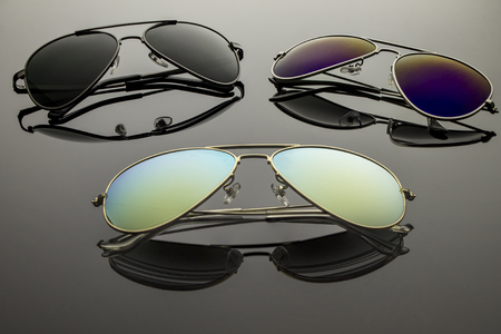 Sunglasses different in shape and color pairs on a dark background with reflectionの写真素材