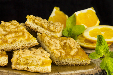 Cookies with marmalade decorated with mint leaves and orange slices on a black background with reflectionの写真素材