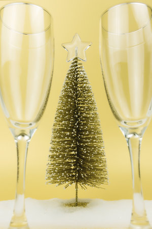 Glasses for sparkling wine, christmas tree, fake snow, gold backgroundの写真素材