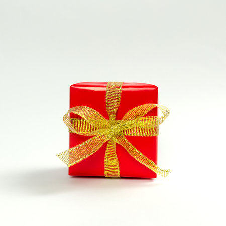 Red gift box with golden ribbon on white backgroundの写真素材