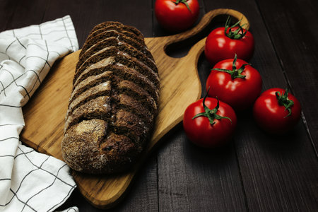 Fresh baked bread and tomatoes on wooden tableの写真素材