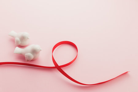 Two white bird with red ribbon on pinkの写真素材