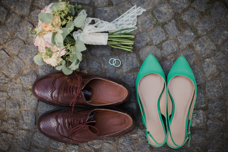 Wedding bouquet, shoes, rings on the stone tile