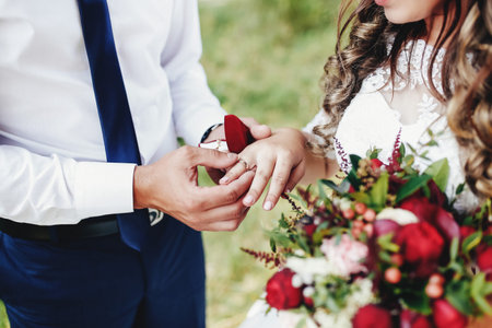 The groom puts the wedding ring on the bride finger. Wedding bouquet