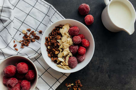 Frozen strawberry with granola, almond flakes, cream on concrete tableの写真素材