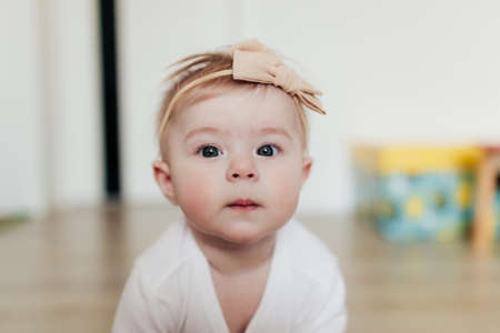 Little baby girl with bow looking at camera. Blurred backgroundの写真素材