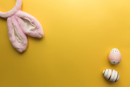 Pink Easter bunny ears with eggs on the yellow background