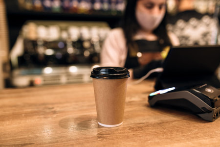 Buying a cup of coffee in a cafe, barista, NFC terminal. Blurred background