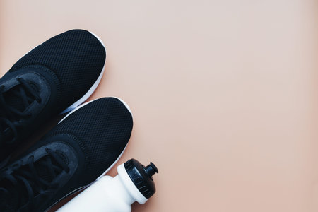 Sports sneakers for running, water bottle on beige background. High quality photo