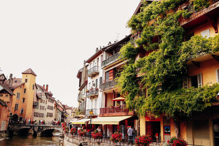 Annecy city water channel, red flowers, old buildings, bridge, green balconies. High quality photoの写真素材