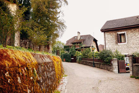 Beautiful street in Annecy with a stone fence with moss, old buildings. High quality photoの写真素材