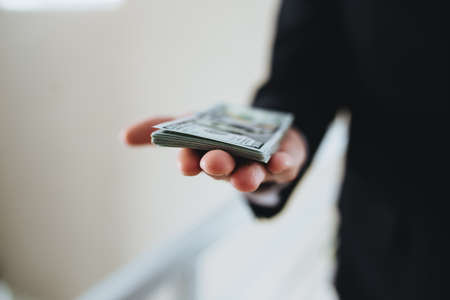 One hundred dollar bills money bundle, in hand of man in suit and white shirtの写真素材