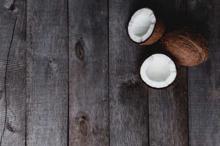 Broken coconuts on gray wooden background. White coconut pulp. High quality photoの写真素材