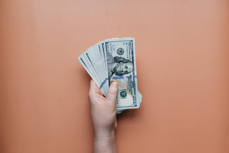 Bundle of dollars in hand on beige background. High quality photo