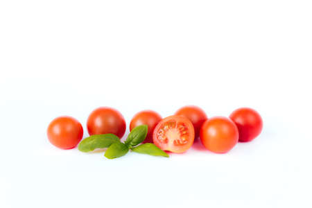 Red cherry tomatoes with green basil on a white background. High quality photoの写真素材