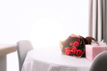 A bouquet of red tulips on the table and pink gift box. Concept for a greeting card. High quality photoの写真素材