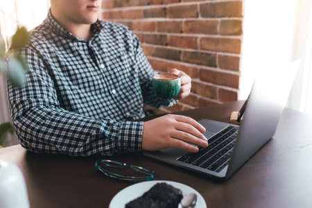 Man working at the laptop with a cup of coffee at home. Blurred background. High quality photoの写真素材