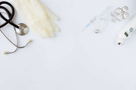 Medicine treatment, vaccination concept. Bottle with vaccine and injection syringe, electronical thermometer, stethoscope and vaccine vials on white background. High quality photoの写真素材