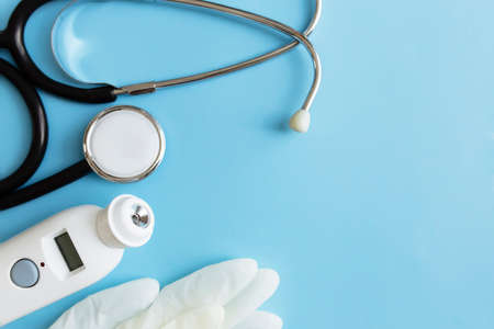 Medicine treatment concept. Electronic thermometer, phonendoscope or stethoscope, white gloves on blue background. High quality photoの写真素材