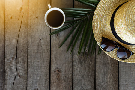 Travel, vacation concept. Hat, palm leaf, coffee, eyeglasses, wooden backgroundの写真素材