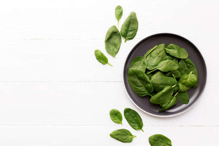 Bowl with fresh green salad leaves of spinach on a white background. Healthy vegetarian eating concept. High quality photoの写真素材