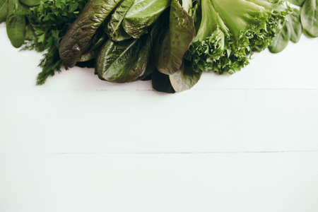 Flat lay with fresh green salad leaves of spinach, lettuce, romaine on white background. Healthy vegetarian eating concept. High quality photoの写真素材