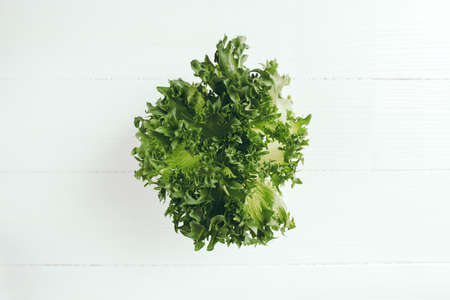 Flat lay with branch of fresh green salad leaves of lettuce salad on a white background. Healthy vegetarian eating concept. High quality photoの写真素材