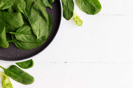 Bowl with fresh green salad leaves, spinach, lettuce, basil on a white background. Healthy vegetarian eating concept. High quality photoの写真素材