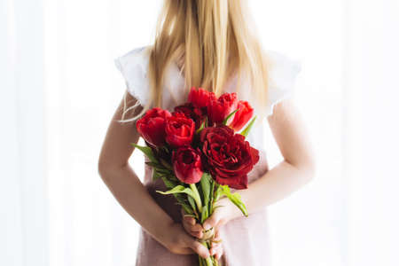 Small girl holding bouquet of red tulip flowers. Concept for greeting card for Easter, Mother's day, International women's day, Saint Valentine's day. High quality photoの写真素材