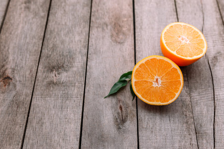 Flat lay with fresh ripe sliced halves of orange fruit on gray wooden background. Orange pulp and green leaves. Tropic food concept. Healthy eating concept. High quality photoの写真素材