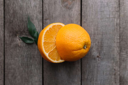 Flat lay with fresh ripe sliced halves of orange fruit on gray wooden background. Orange pulp and green leaves. Tropic food concept. Healthy eating concept. High quality photoの写真素材