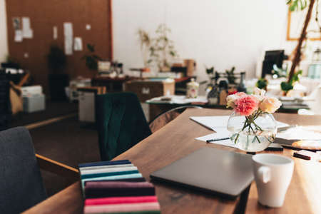 Interior designer workplace with laptop and fabric color palette. Oak wooden table. Cup of coffee, Flowers in vase. High quality photoの写真素材