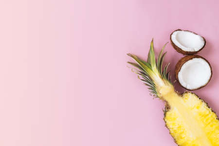 Flat lay with cut halves of fresh pineapple, coconut on a pastel pink background. Ingredient for Pina Colada. Exotic fruit. High quality photoの写真素材