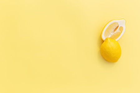 Two halved cuts of lemon with shadow on yellow background. Healthy eating, travel or vacation concept
