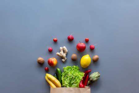 Healthy and organic food flay lay concept on gray background. Eco bag with lettuce salad leaves,...