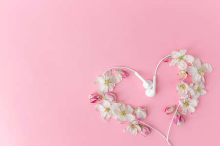 Flat lay on pink background with apple blossom heart shape and earphonesの写真素材