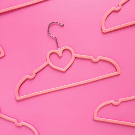 Black Friday or clothing industry concept on pink background flat lay with randomly scattered pink clothes hangers pattern with heart shape on hangerの写真素材