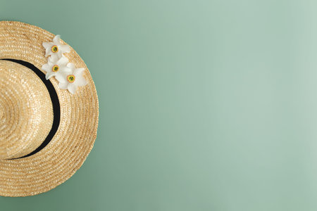 Summertime collection concept flat lay on green background with straw hat and flower heads of...