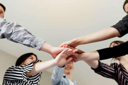 Friendly group of people doing handshake and cross hands. Friendship, agreement, cooperation concept with young teens crossing their handsの写真素材