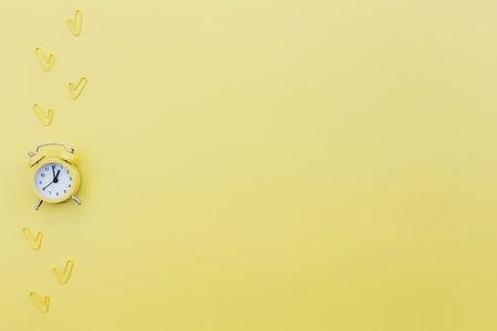 Back to school, office work conceptual flat lay with alarm clock, clips and copy space area for text. Concept of time to work, be in time and wake up early idea. Yellow background and alarmclockの写真素材