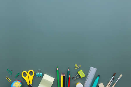 Back to school conceptual flat lay with different office supply objects on green background. Concept for primary and secondary school pupil. Scissors, pen, pencil, eraser, ruler, note, clipの写真素材