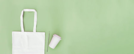 Eco white craft paper bag, metal drink straw, coffee cup on green background flat lay with copy...