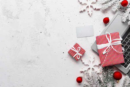 Christmas, New Year shopping gray concrete flat lay. Laptop computer, empty blank credit card, red white paper present gift boxes top view. Fir branch, toy balls, stars. Copy space area on photoの写真素材