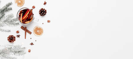 Christmas banner flat lay on white gray background with glass cup or mug of Mulled Wine, present red gift box, decorations, cinnamon, orange, apple, various spices, fir, cone, anise. Conceptual photoの写真素材