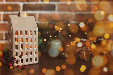 Christmas candle in form of house or home, blurred Christmas fir tree lightsの写真素材