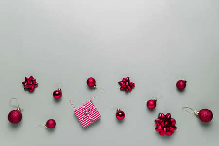 Gray background with pink Christmas gift box, red ball toys, spheres, bowsの写真素材
