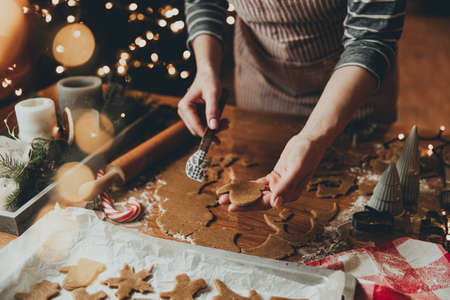 Merry Christmas, Happy New Year. Gingerbread cookies cooking, baking. Young woman sculpts, cuts and carves gingerbread cookie figures from kneaded dough using special kitchen forms. High quality photoの写真素材