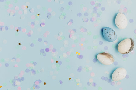 Happy Easter holiday, coming spring concept. Flat lay with white, colorful quail eggs, feather. Blue...